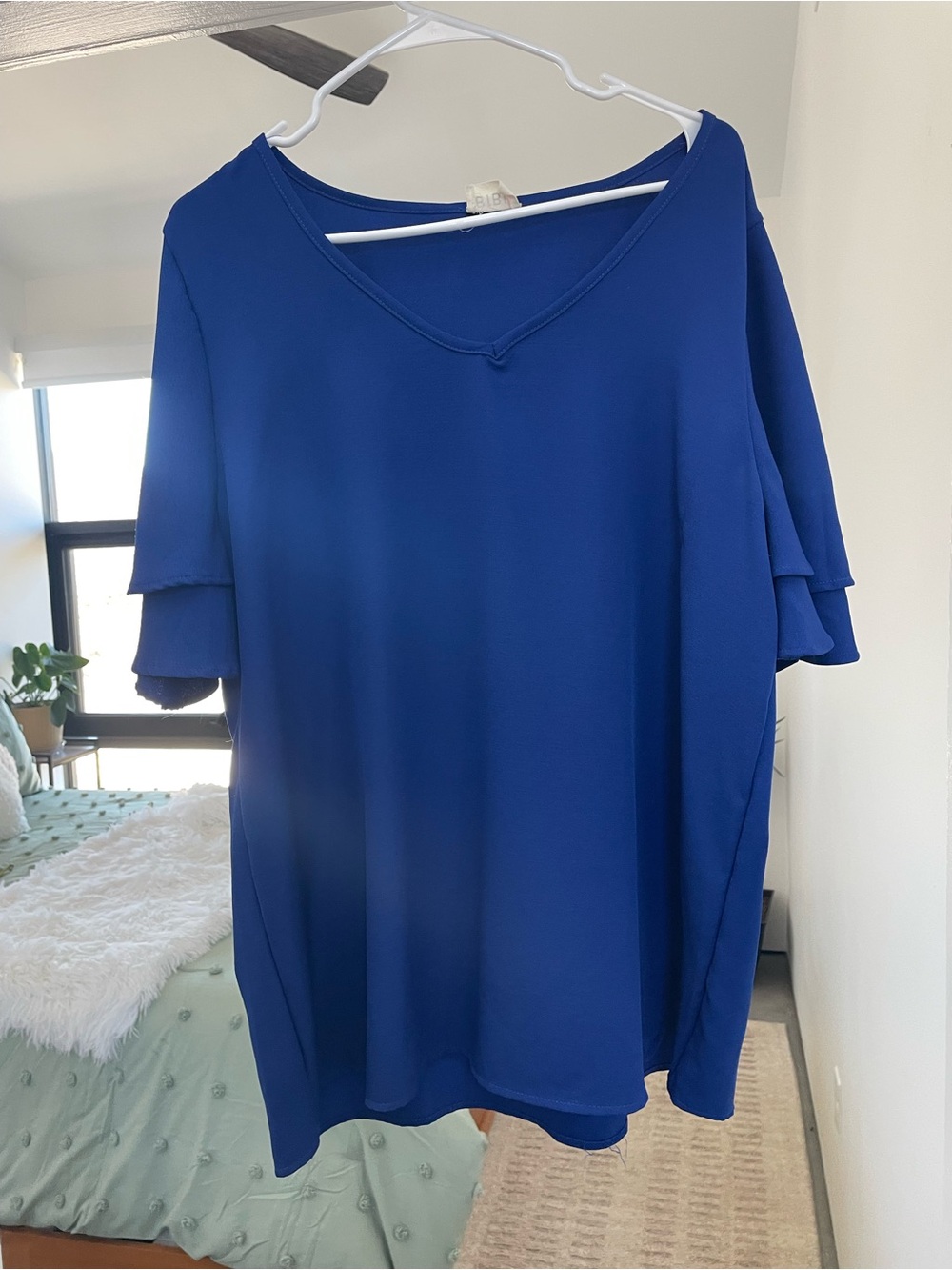 Blue V-neck top featuring tiered ruffle sleeves.